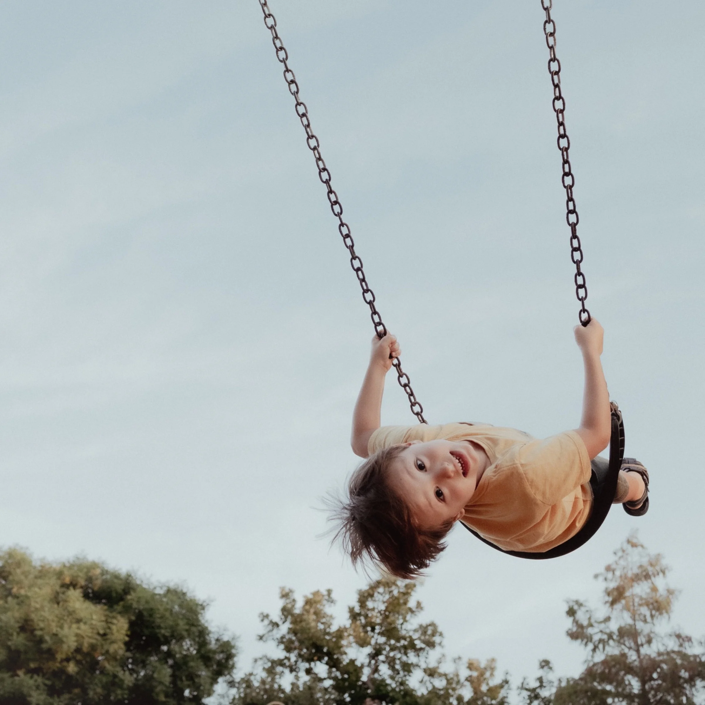 Toddler laughing on a swing outdoors