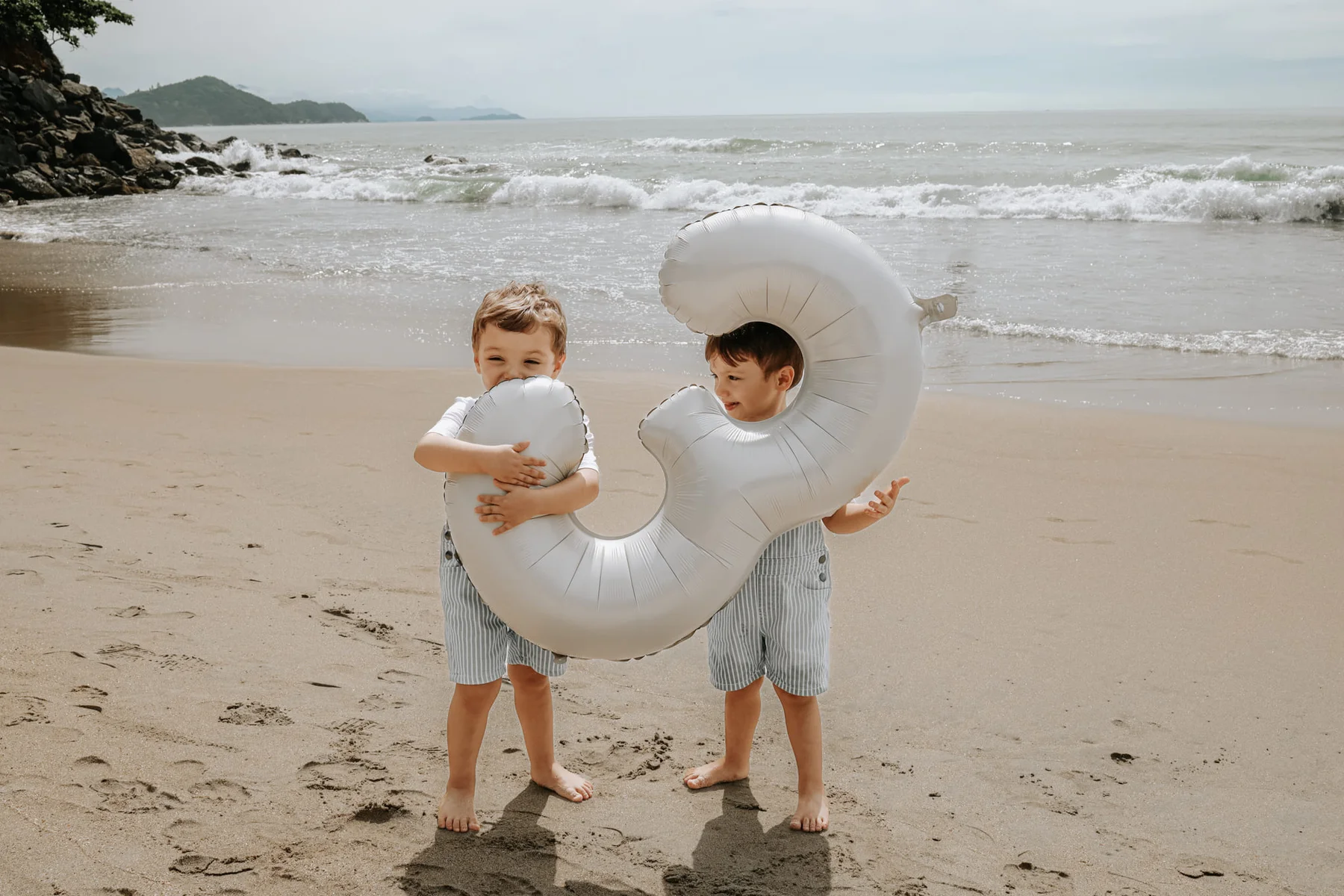 Two brothers playing with a giant balloon letter at the beach