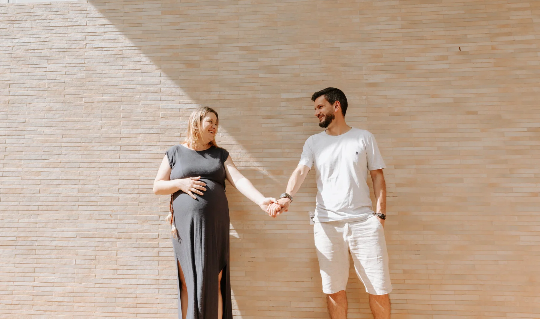 Expecting parents holding hands outdoors, maternity portrait